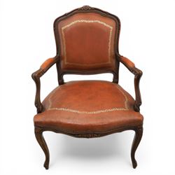 Pair of late 20th century French style carved beech open armchairs, the shaped and moulded frames with foliate cresting rail above padded backs and overstuffed seats upholstered in tan leather with gilt foliate borders and close nailed trim, raised upon cabriole supports with acanthus carved knees