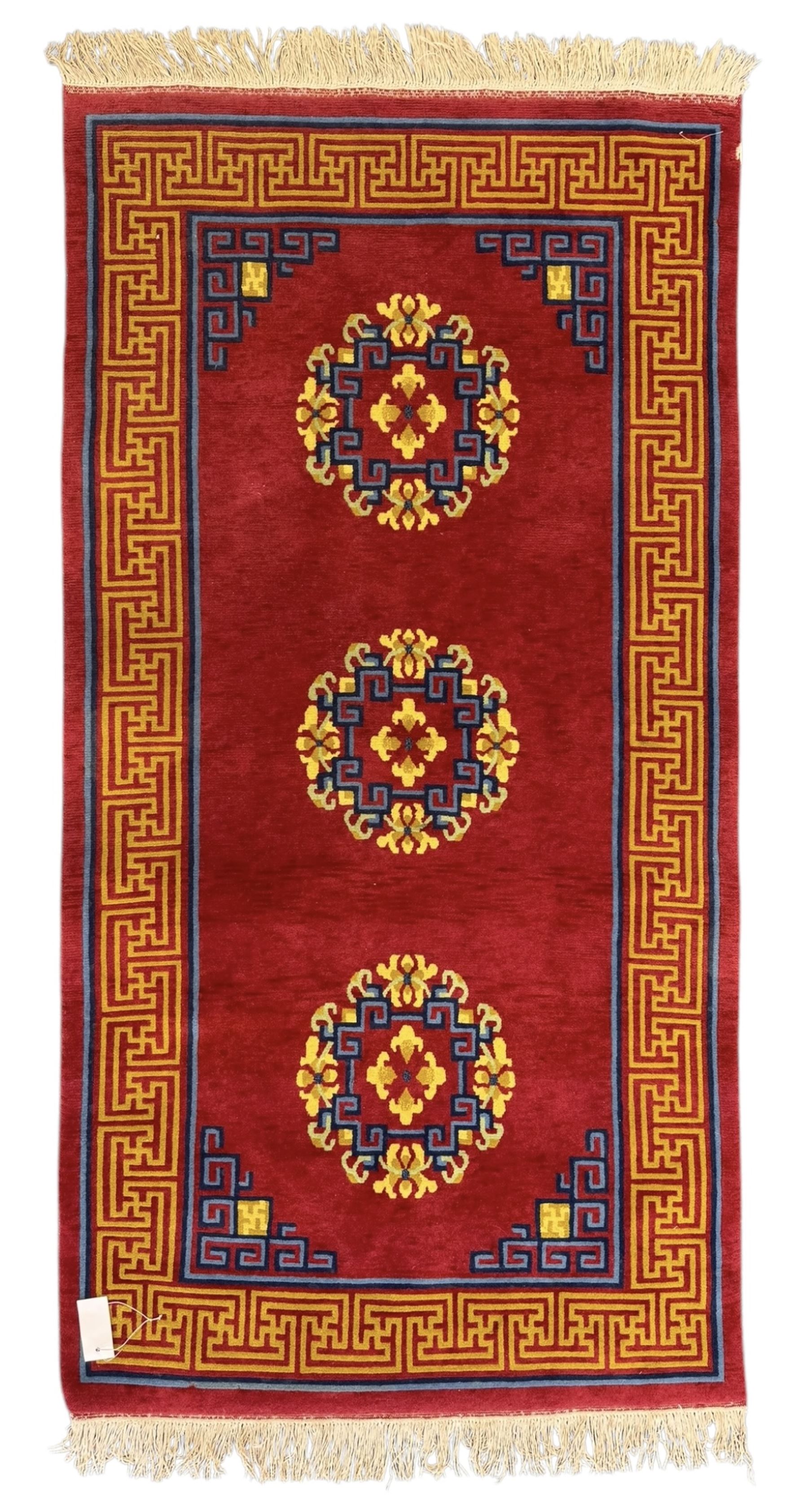 Tibetan-design handwoven rug, deep red field with three central medallions in yellow and blue, traditional yellow key border, white fringes on both ends