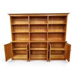 Philip Koomen (1953-) - Craftsman-made modern cherrywood large open
bookcase with a cupboard base, upper section with a
shaped cornice above three sections with two open
shelves, the lower section has three cupboards,
each with two panelled doors enclosing a single
shelf, raised on a plinth base