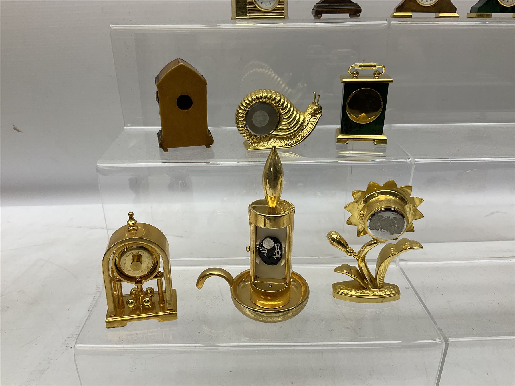 Collection of miniature clocks, predominantly with quartz movements, to include example modelled as an armchair, Edinburgh crystal glass example, clock modelled as a flower, sewing machine etc