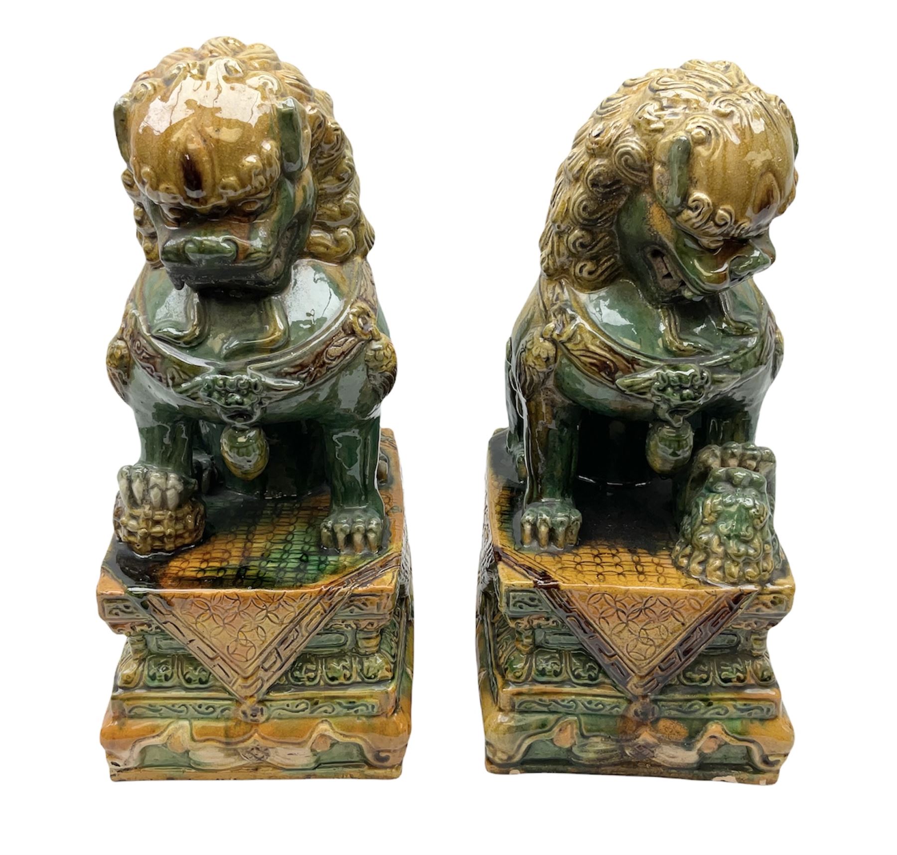 Pair of Chinese Temple Lions or Dogs of Foo, modelled in seated post, one with one front paw resting upon a ball, the other upon a cub, each upon stylised plinth base, H44cm