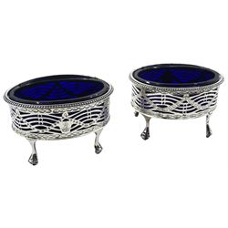 Pair of George III silver open salts, of oval form with beaded rim, the pierced sides detailed with husk swags and engraved lower band, upon four claw feet, hallmarked J Hoyland & Co, Sheffield 1777, with blue glass liners, H5cm W8cm, approximate silver weight 2.71 ozt (84.4 grams)