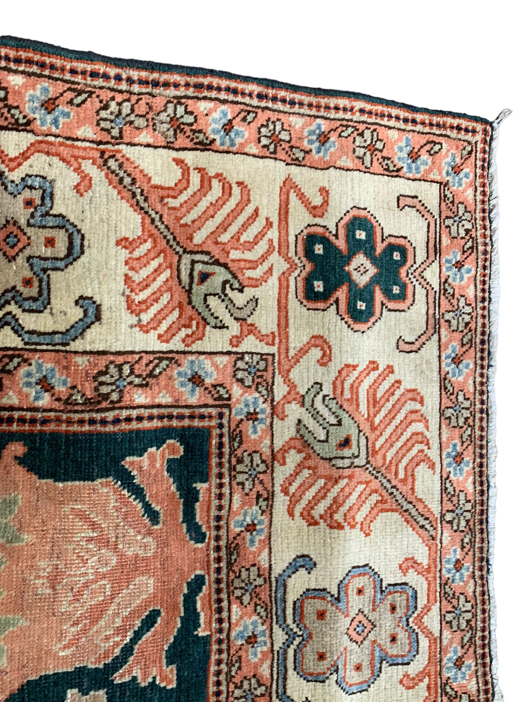 Persian emerald green ground rug, the field decorated with large stylised plant motifs, ivory ground border with repeating leaf motifs, the guards decorated with trailing branch and flowerhead motifs