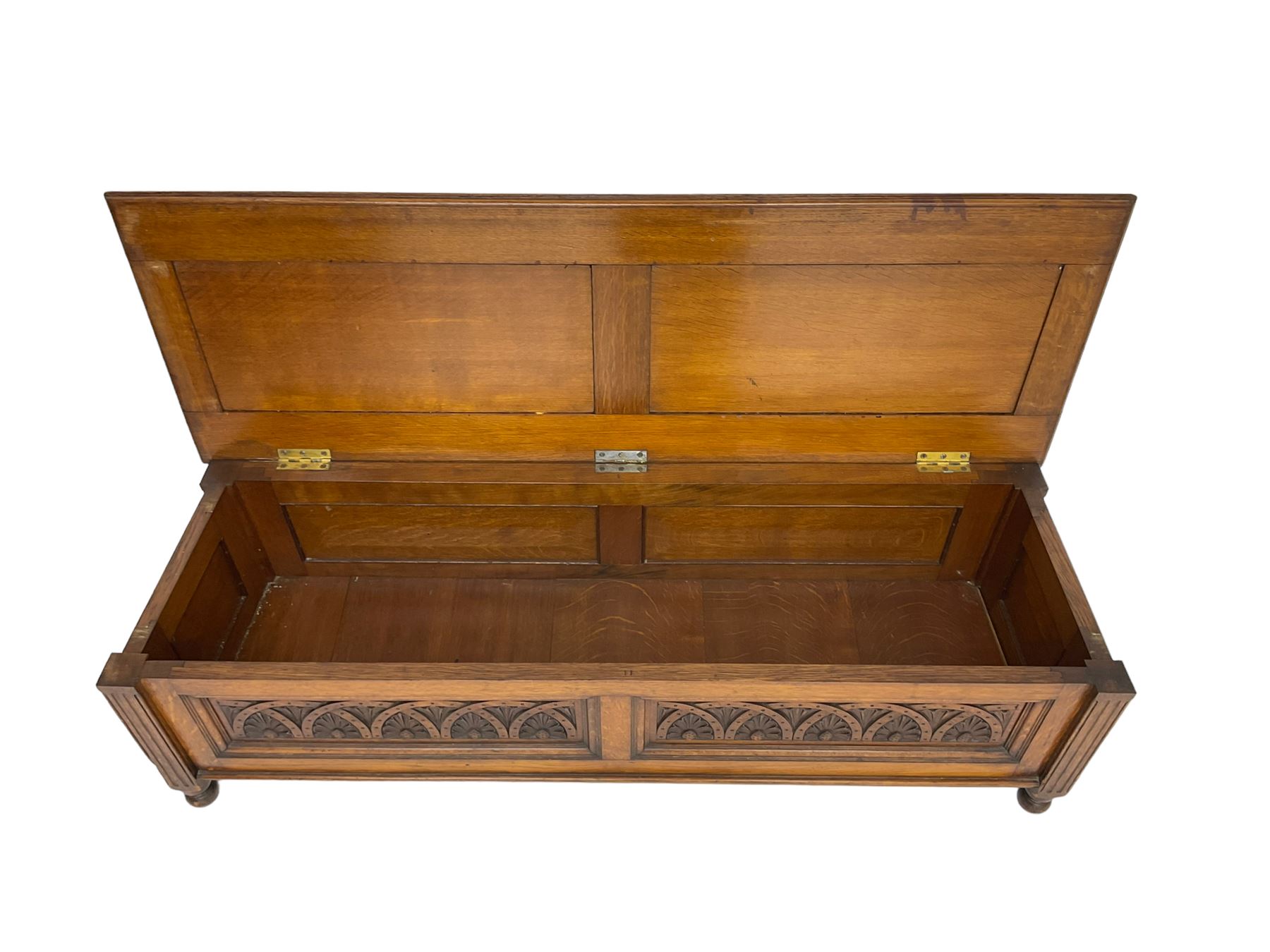 Early 20th century oak ‘bay window’ shaped blanket chest or coffer, hinged top, the front with two lunette carved panels flanked by fluted uprights, on turned feet