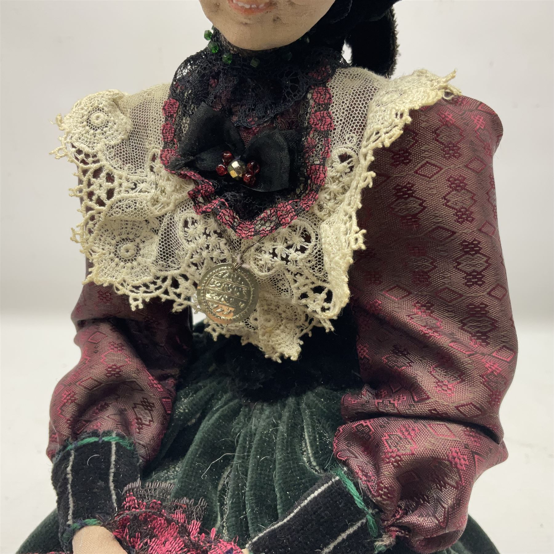 Anna Meszaros Hungary - hand made needlework finely detailed figurine of a pensive old lady seated on a stool wearing a lace trimmed long black and maroon dress and hat, clutching a lace bag H32cm Auctioneer's Note: Anna Meszaros came to England from her native Hungary in 1959 to marry an English businessman she met while demonstrating her art at the 1958 Brussels Exhibition. Shortly before she left for England she was awarded the title of Folk Artist Master by the Hungarian Government. Anna was a gifted painter of mainly portraits and sculptress before starting to make her figurines which are completely hand made and unique, each with a character and expression of its own. The hands, feet and face are sculptured by layering the material and pulling the features into place with needle and thread. She died in Hull in 1998.