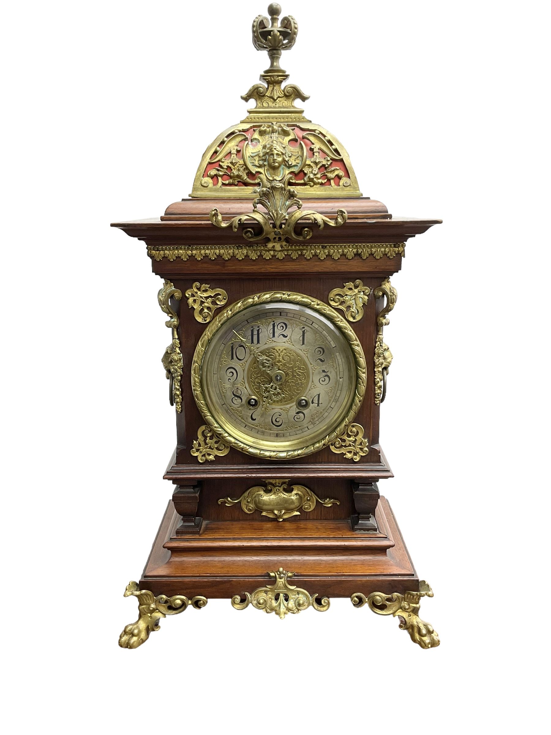 Lenzkirch - Edwardian German 8-day  mantle clock in an oak case with brass mounts and a pierced dome pediment with finial, silvered dial with Arabic numerals, gilt hands and dial centre, rack striking movement, striking the hours and half-hours on a coiled gong. With pendulum and key.