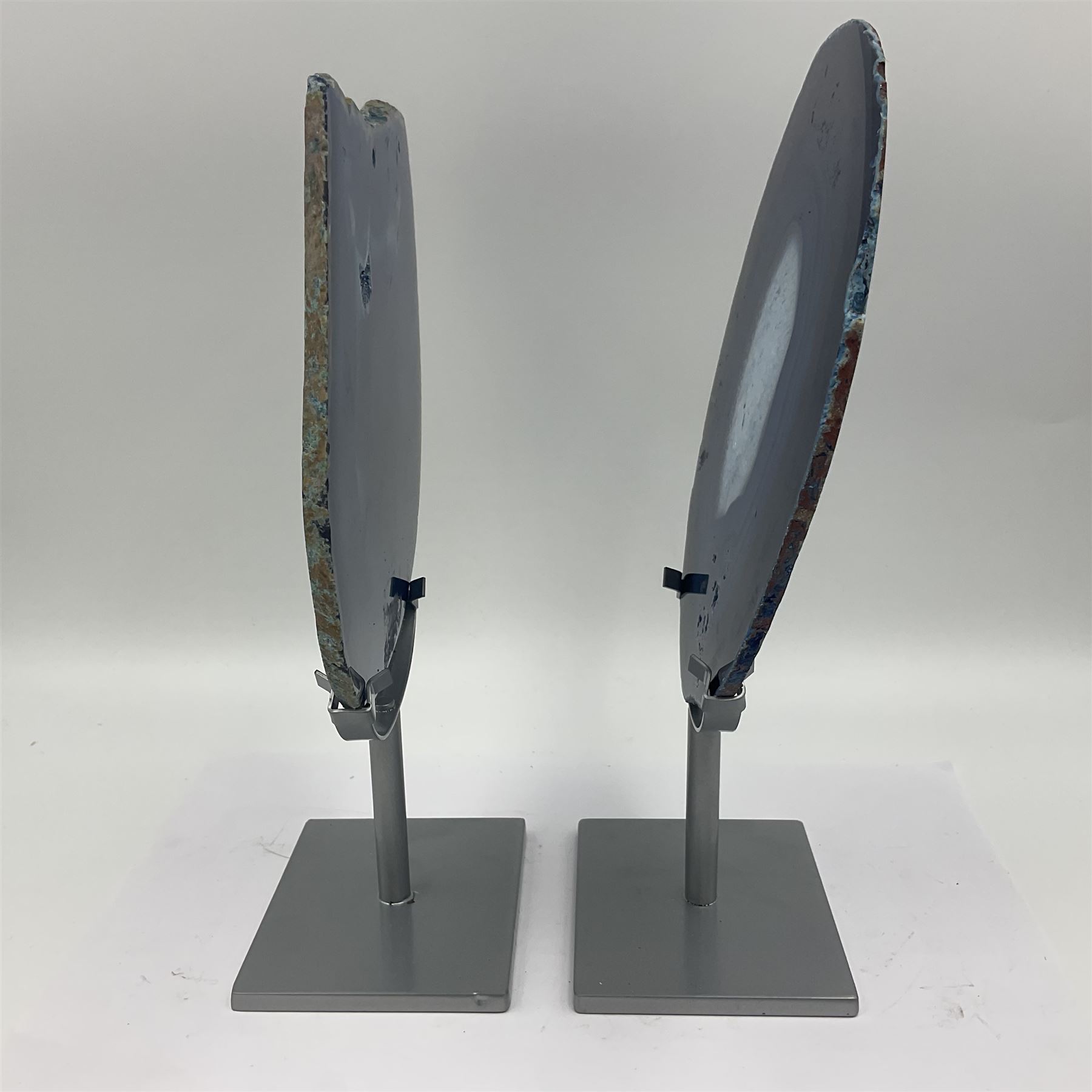 Pair of blue agate slices, polished with rough edges, raised upon silvered metal stands, H26cm