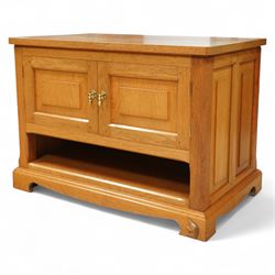 Unicornman - Yorkshire oak media cabinet, rectangular top over a pair of panelled cupboard doors with brass handles, open undertier, on shaped bracket supports above castors