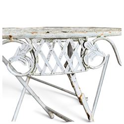 Three-piece French style white-painted wrought iron garden bistro set, comprising a circular folding table with latticework top and apron with scrolling foliate motifs (W70cm H80cm) and matching pair of chairs, with scrolling cresting rail and acorn finials over a scrolled foliate medallion, raised on lattice seat and folding X-frame base (W42cm H93cm)