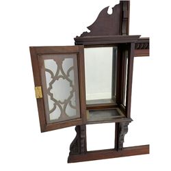 Late Victorian walnut overmantel mirror, raised relief carved pediment over bevelled mirror panels and two cabinets enclosed by glazed doors  