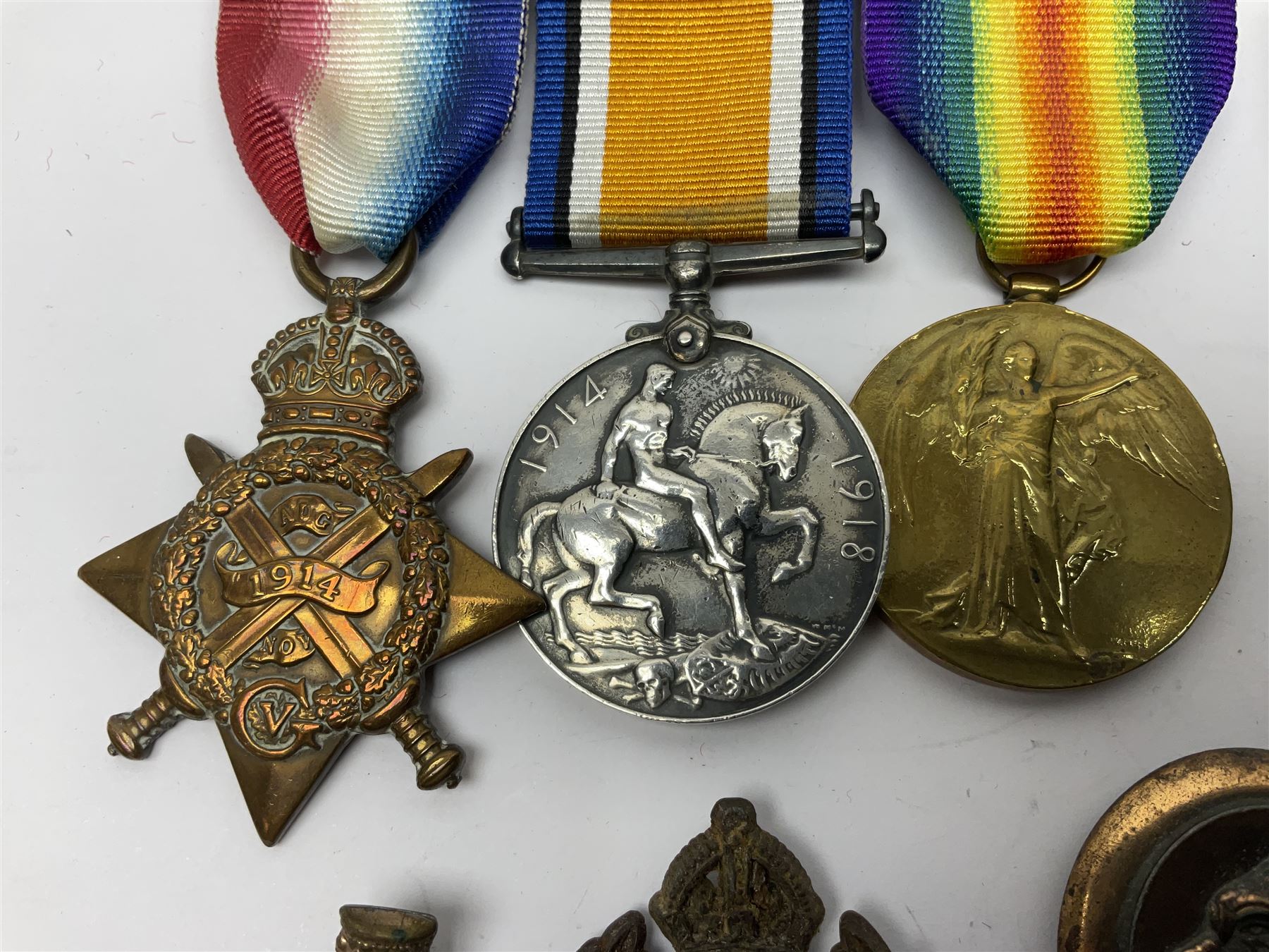 Made-up group of three WWI medals comprising 1914 Star awarded to 23598 Gnr. F. Jefferson R.G.A., British War Medal and Victory Medal with names removed; with ribbons on wearing bar; 1942 Motorist's Medal and small quantity of cap badges, Royalty badges etc