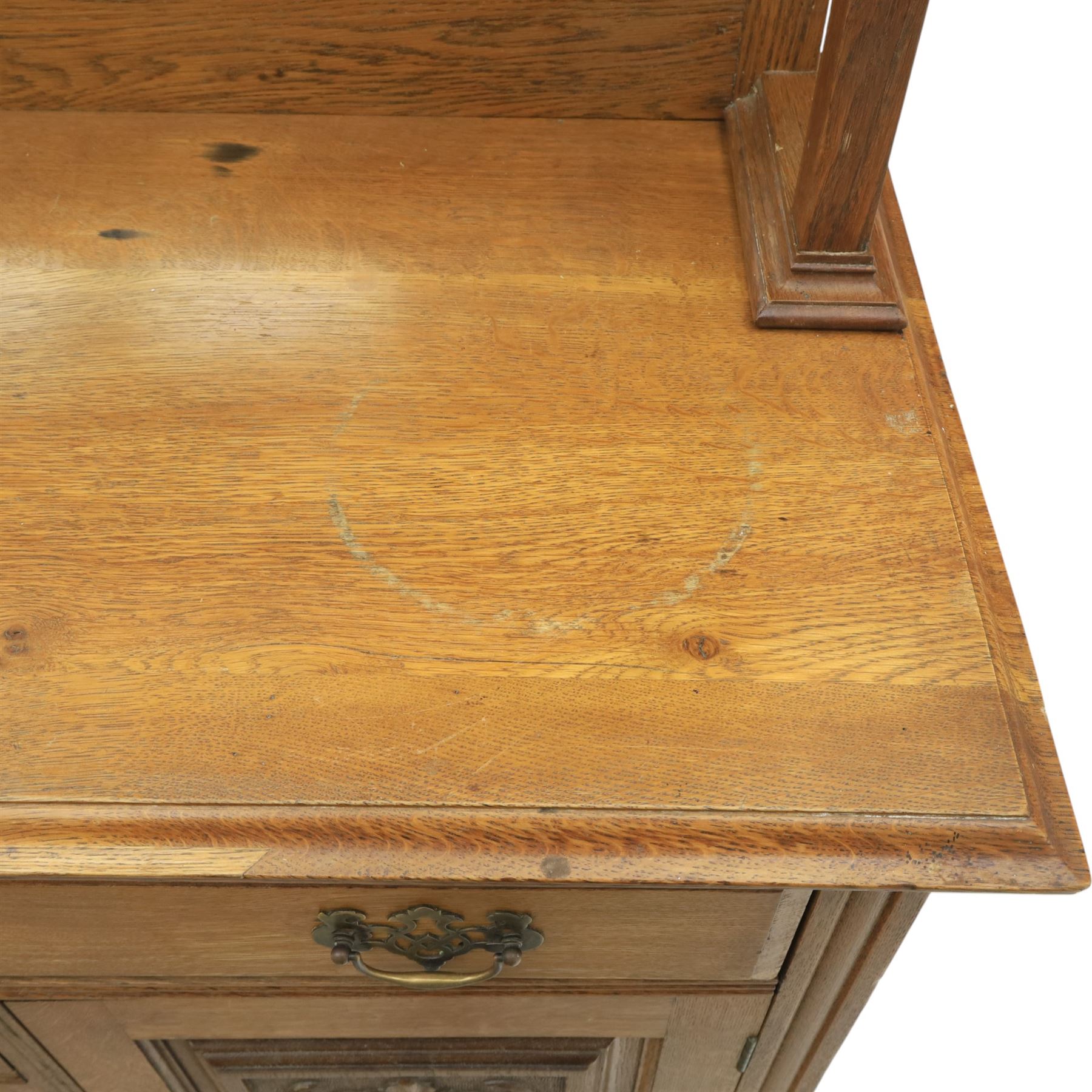 Arts and Crafts oak mirror back sideboard, the bevelled rectangular mirror set within a back with foliate carved panels, with turned baluster and knopped supports, upon a base with moulded top above three drawers  and three cupboard doors, two with carved foliate detail, upon four shaped bracket feet