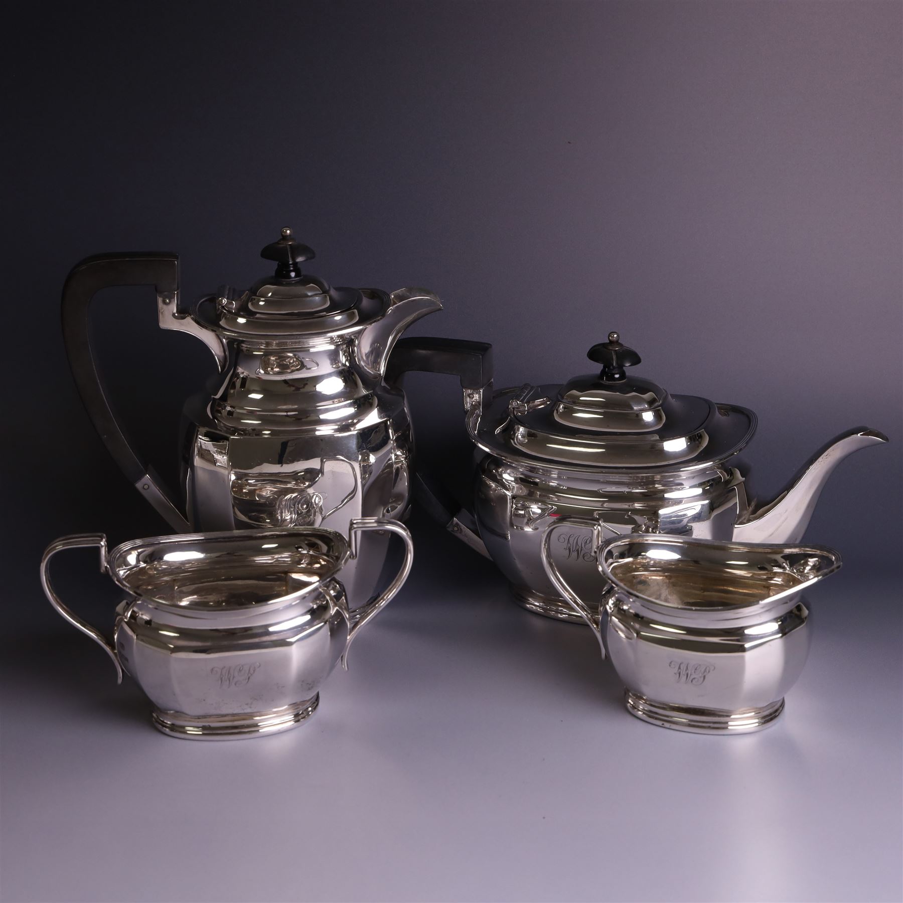 1930s silver four piece tea service, comprising teapot, hot water pot, sugar bowl and milk jug, each of part faceted oval form with engraved monogram to body, the teapot and hot water pot with Bakelite type handles and finials, hallmarked Atkin Brothers, Sheffield 1933