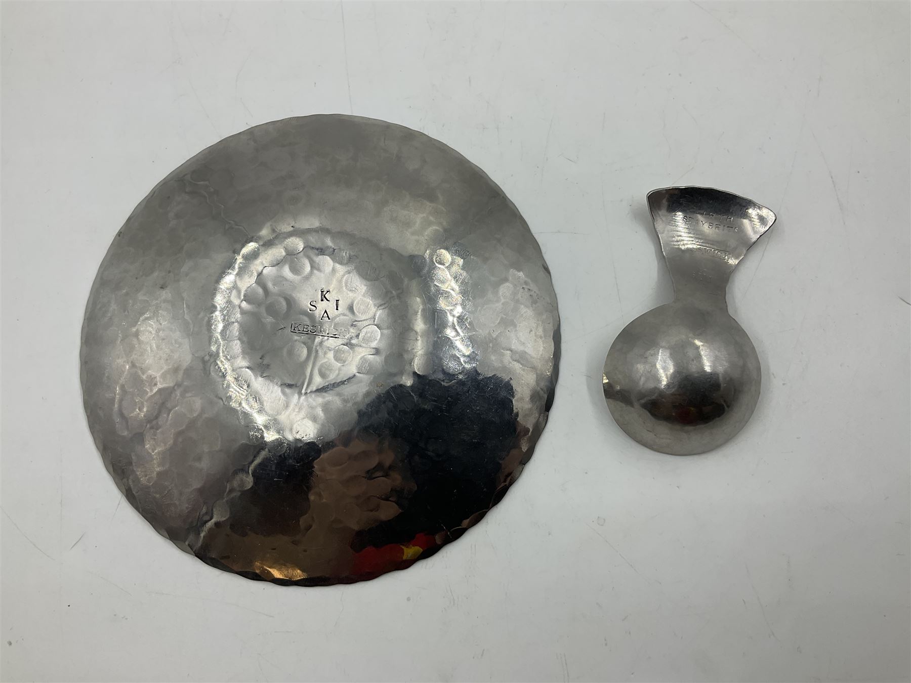 Keswick School of Industrial Arts (KSIA), Arts and Crafts hammered steel Staybrite caddy spoon, L6.5cm, and dish with engraved fern decoration to centre, D11.5cm, both with impressed marks beneath