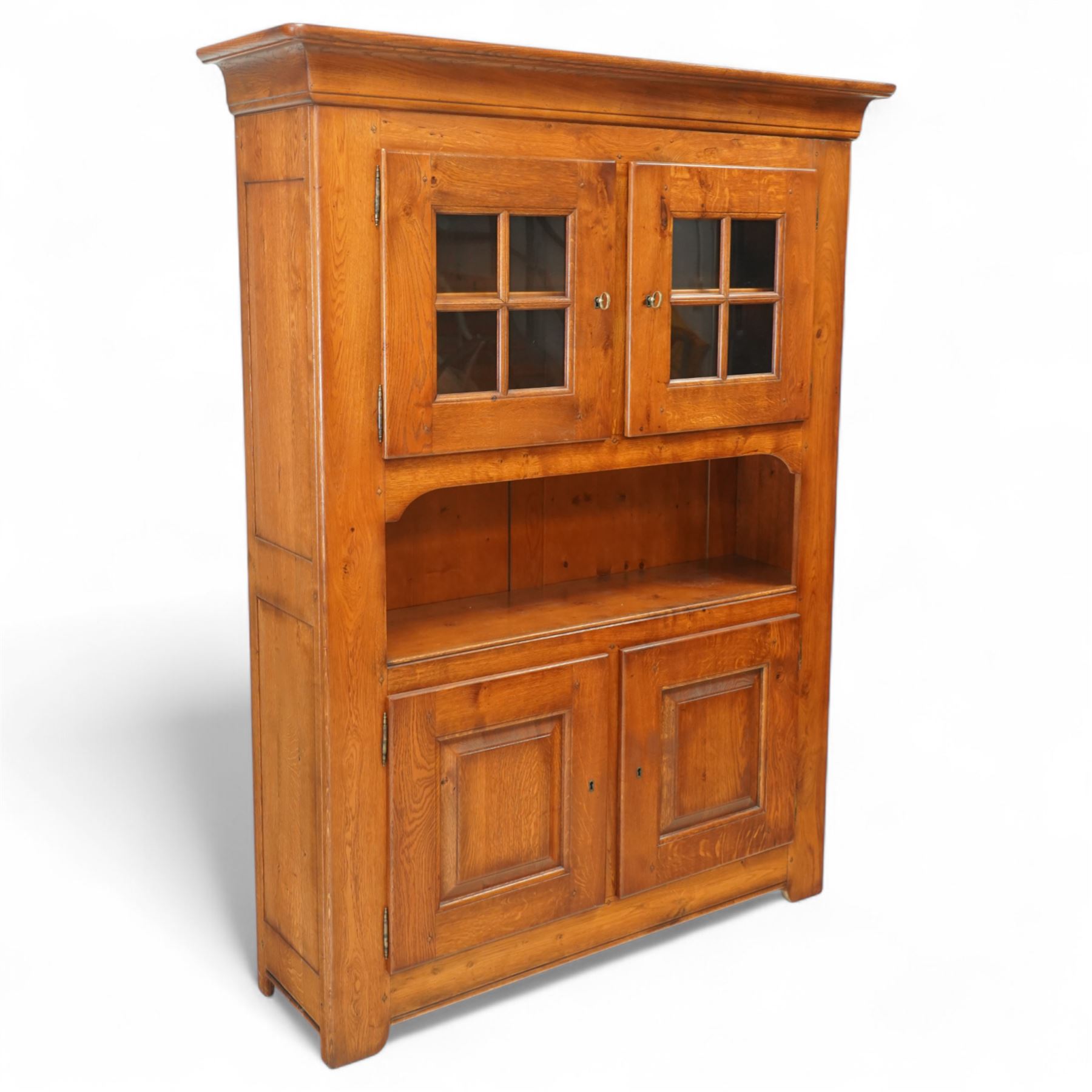 Traditional design solid oak dresser, moulded cornice over twin glazed doors enclosing shelved interior, open centre section, lower base with fielded panel doors opening to shelved cupboards, on plinth base