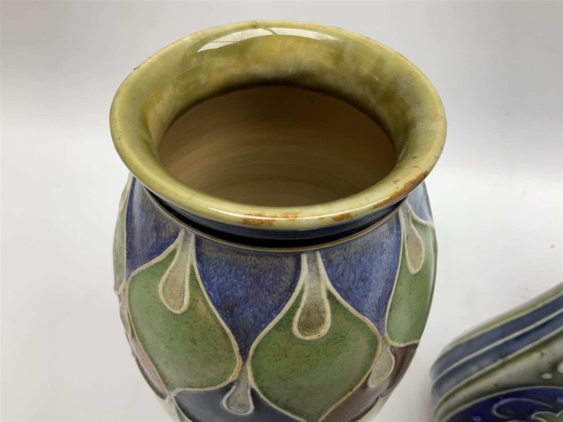 Two Royal Doulton stoneware vases, the first example with tubelined floral decoration, the second with Art Nouveau decoration, together Doulton Lambeth vase of flattened form with foliate decoration on a green ground, all with impressed mark beneath, tallest example H26cm