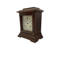 An American Mantle clock in a mahogany case with an eight-day “Ansonia” striking movement, case with a flat top and reeded pillars on a broad plinth with raised feet, square engraved and silvered dial with roman numerals and minute track, steel spade hands and pendulum regulation, sounding the hours and half hours on a coiled gong. With pendulum and key.  





