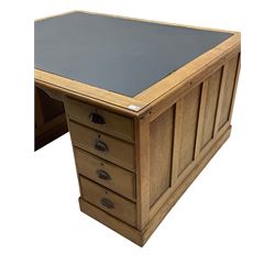 Early 20th century oak twin pedestal partners desk, the moulded rectangular top with inset leather, each side fitted with four drawers and cupboard with panelled door, plinth base

