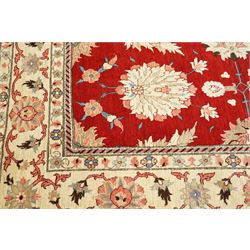 West Persian Sarough hand-knotted carpet, rich madder red field, decorated with stylized palmettes angular vinery and floral sprays within multiple borders of ivory ground and scrolling foliate decoration, with cotton fringe ends 