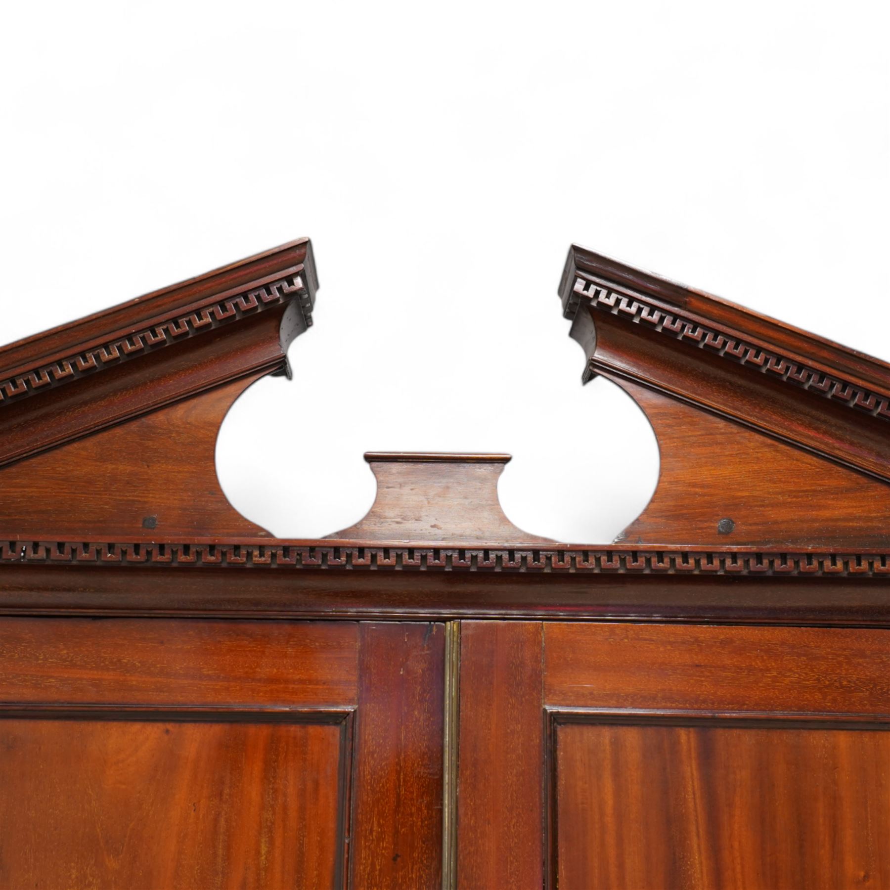 George III mahogany wardrobe, broken sloped arch pediment with dentil moulding over two panelled doors, the base fitted with two cock-beaded drawers, on bracket feet, knock-down construction 