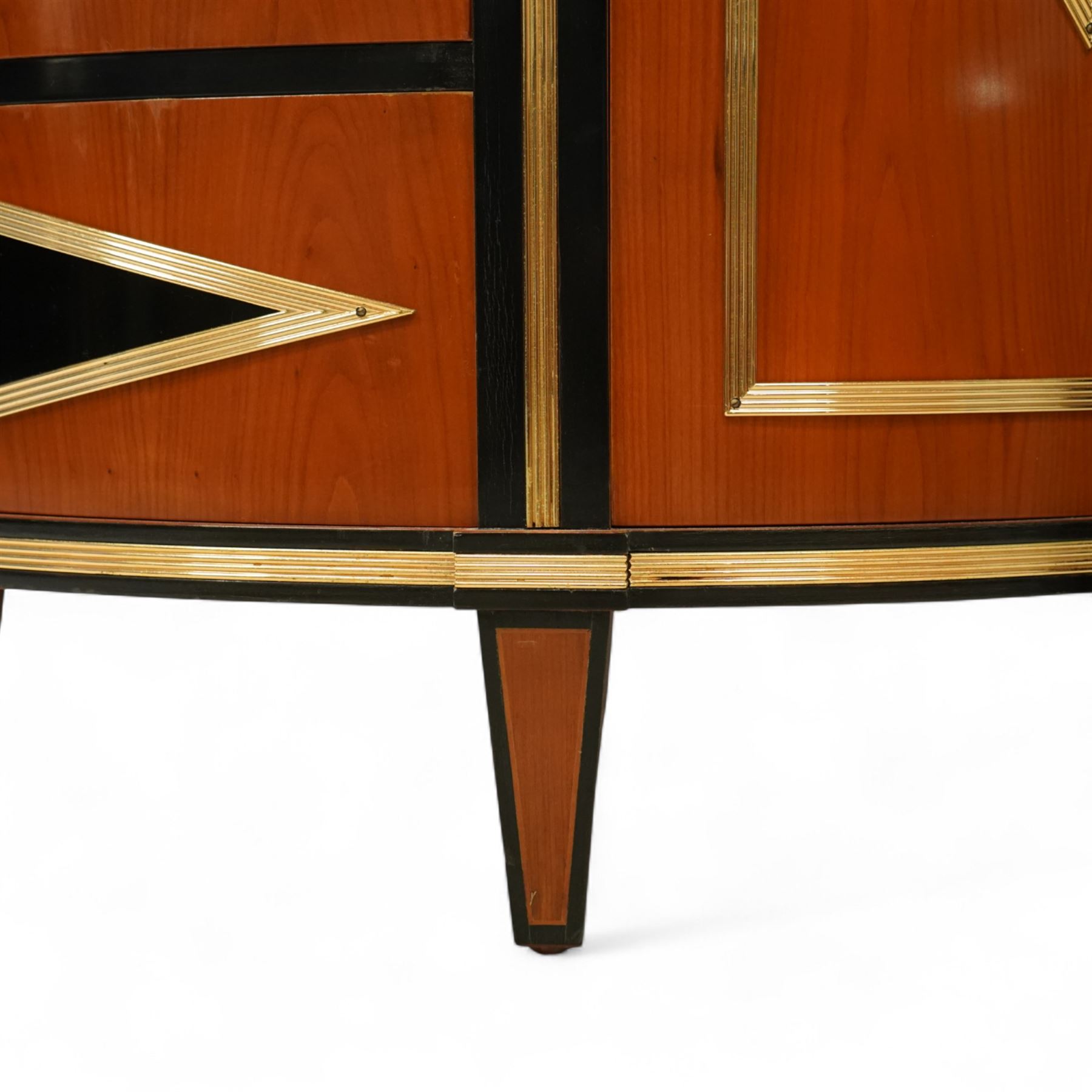 Colombo Mobili - Pair of Italian designer cherrywood art-deco inspired demi-lune commode cabinets, the shaped top with ebonised inlay and gilt brass repeating anthemion beading above a gilt brass reeded moulding, over three long drawers with gilt brass geometric panel mounts, flanked by cupboard doors with diamond motif, raised on tapering square supports 
