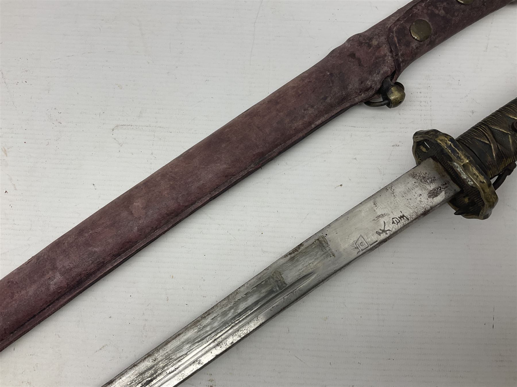 Copy of a WWII Japanese NCO sword, the 65cm slightly curving blade stamped with pseudo Japanese characters and cast brass simulated cord bound grip; in officer's leather bound field scabbard L97cm overall