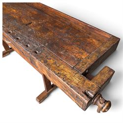 Large early 20th century rustic stained reclaimed pine workbench, the substantial plank top with recessed tool well and two homemade wooden screw vices, above a single frieze drawer and slatted undertier, raised on trestle end supports