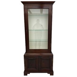 Mahogany display cabinet with hidden compartment, projecting cornice over single glazed door enclosing glass shelves, double panelled cupboard below, the interior with button releasing sliding back compartment, on bracket feet