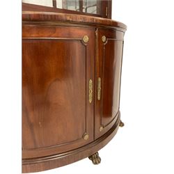 Pair of French Empire design corner cabinets, the straight-front upper section with canted corners and applied half-column pilasters, enclosed by mirror glazed door, the bow-front lower section enclosed by two doors with applied mouldings, mounted by cast metal floral rosettes, skirted base with cast gilt metal hairy paw brass feet