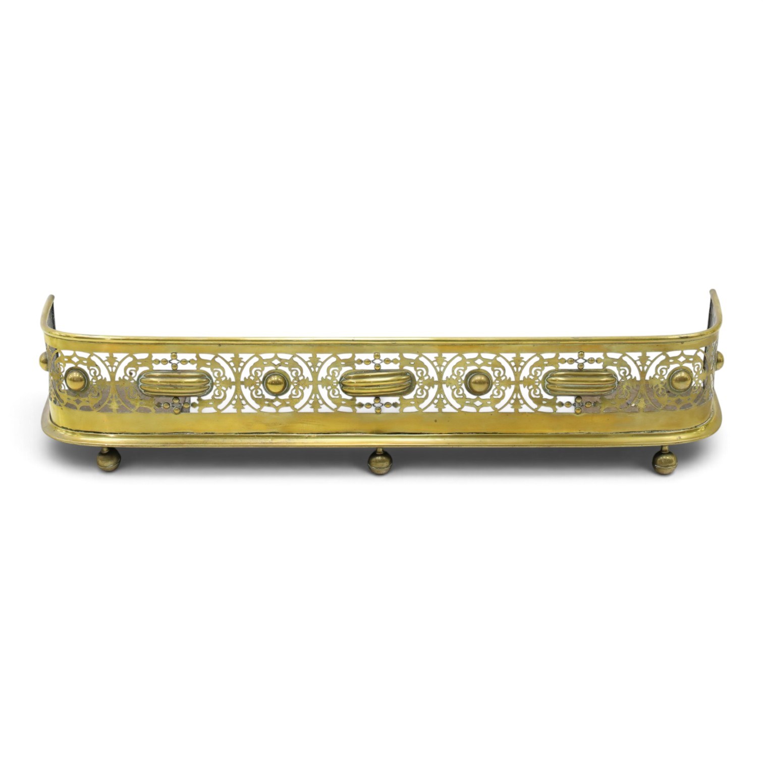 Victorian pierced brass fire fender, the pierced scrolling gallery of Aesthetic taste with applied roundels and protruding lobed mounts, raised on bun feet