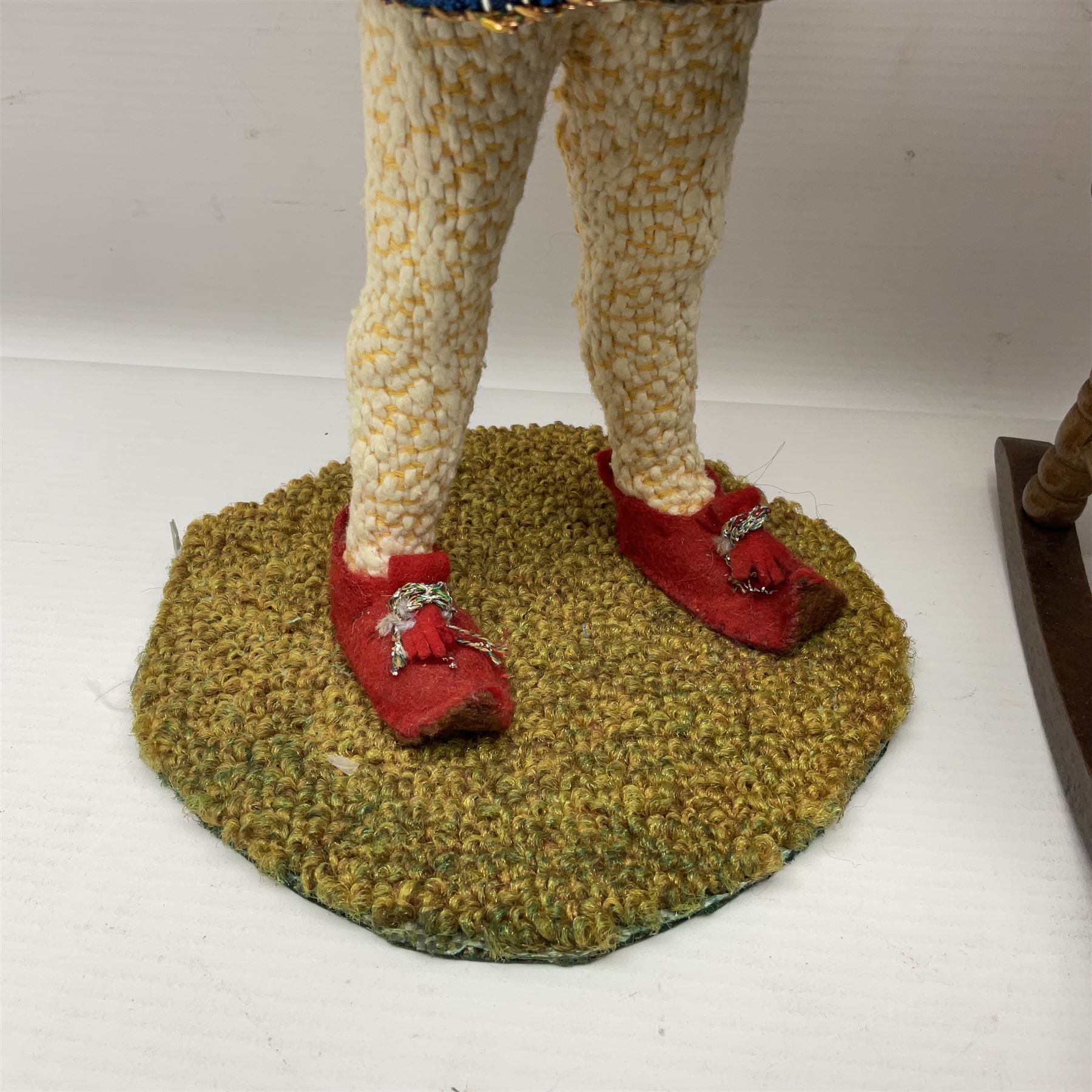 Anna Meszaros Hungary - three hand made needlework figurines - 'The Cobbler' as a child seated in a wooden rocking chair working on a removed boot H28cm; young girl in a long floral dress standing playing a harp H35cm; and young girl wearing a blue tabard standing playing a lute (3) Auctioneer's Note: Anna Meszaros came to England from her native Hungary in 1959 to marry an English businessman she met while demonstrating her art at the 1958 Brussels Exhibition. Shortly before she left for England she was awarded the title of Folk Artist Master by the Hungarian Government. Anna was a gifted painter of mainly portraits and sculptress before starting to make her figurines which are completely hand made and unique, each with a character and expression of its own. The hands, feet and face are sculptured by layering the material and pulling the features into place with needle and thread. She died in Hull in 1998.  