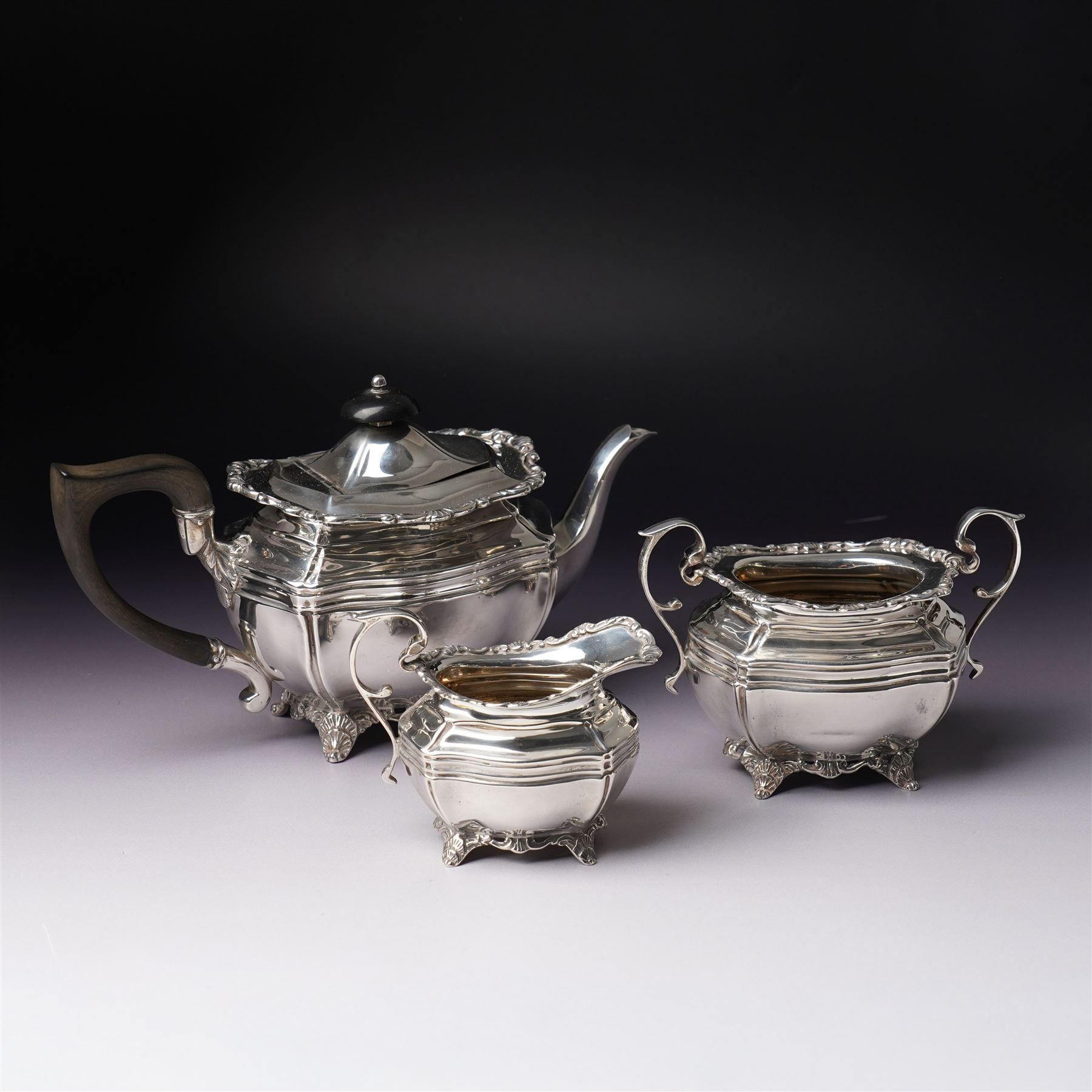 Edwardian silver three piece bachelors tea set of panel sided rectangular form with shell and scroll borders on shell moulded feet London 1903- 1905 Maker Josiah Williams & Co