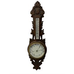 A 1920s oak cased patented aneroid barometer with openwork decorative carving, 8” enamel dial recording air pressure from 26 to 32 inches with weather predictions in gothic script, steel indicating hand and brass recording hand within a brass bezel and flat glass (glass cracked), with a boxed mercury thermometer recording the temperature in degrees centigrade and Fahrenheit.    

