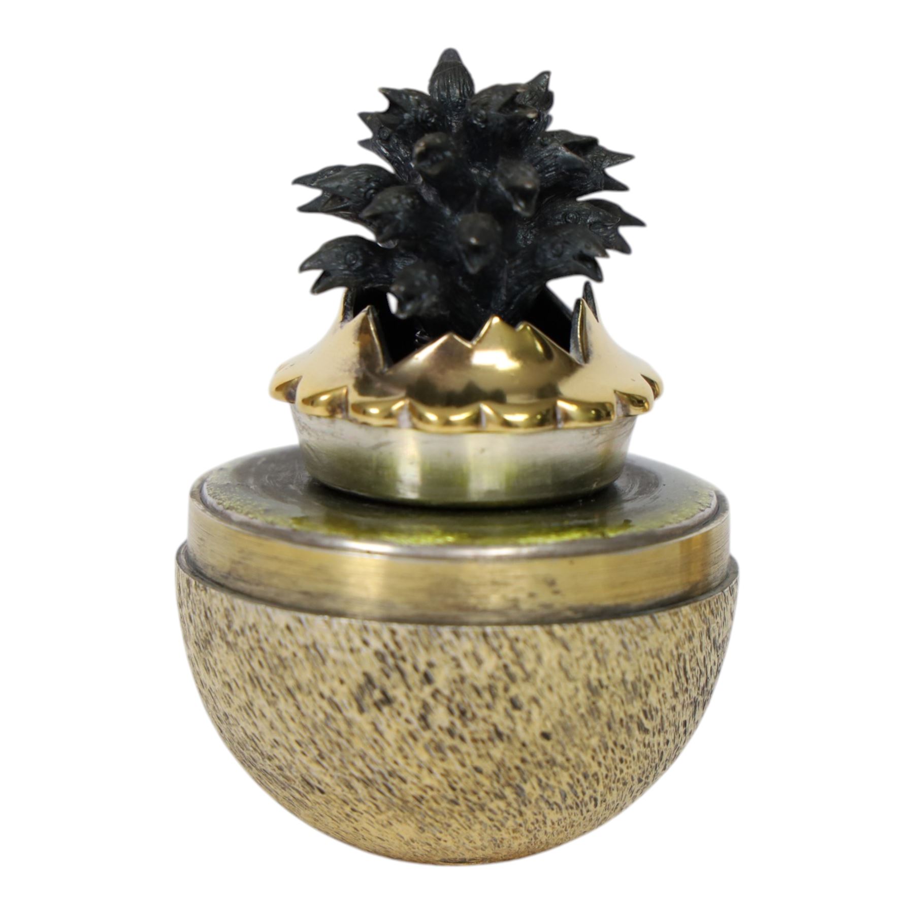 Late 20th century silver and silver-gilt surprise egg, the textured gilt exterior opening to reveal a clutch of chicks, the clustered heads supported upon a spring, within a jagged and lobed silver and gilt encasement, with green enamel surround, hallmarked Stuart Devlin, London 1982, H7cm