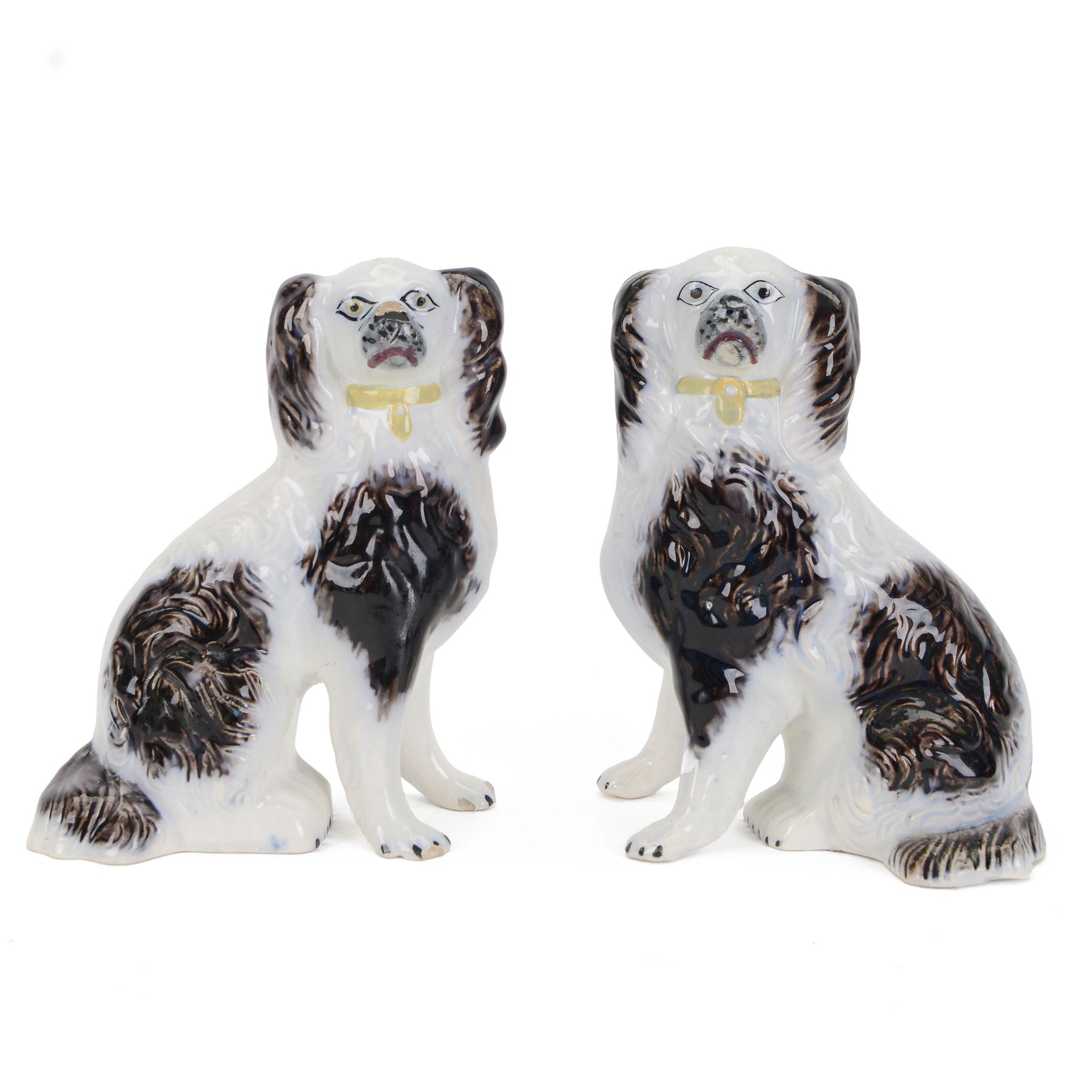 Pair of 19th century slip moulded pottery spaniels, circa 1840-1850, possibly Scottish, modelled with free standing forelegs and moulded fur with dark brown detailing and yellow glazed collars and padlocks upon a white ground, H17.5cm