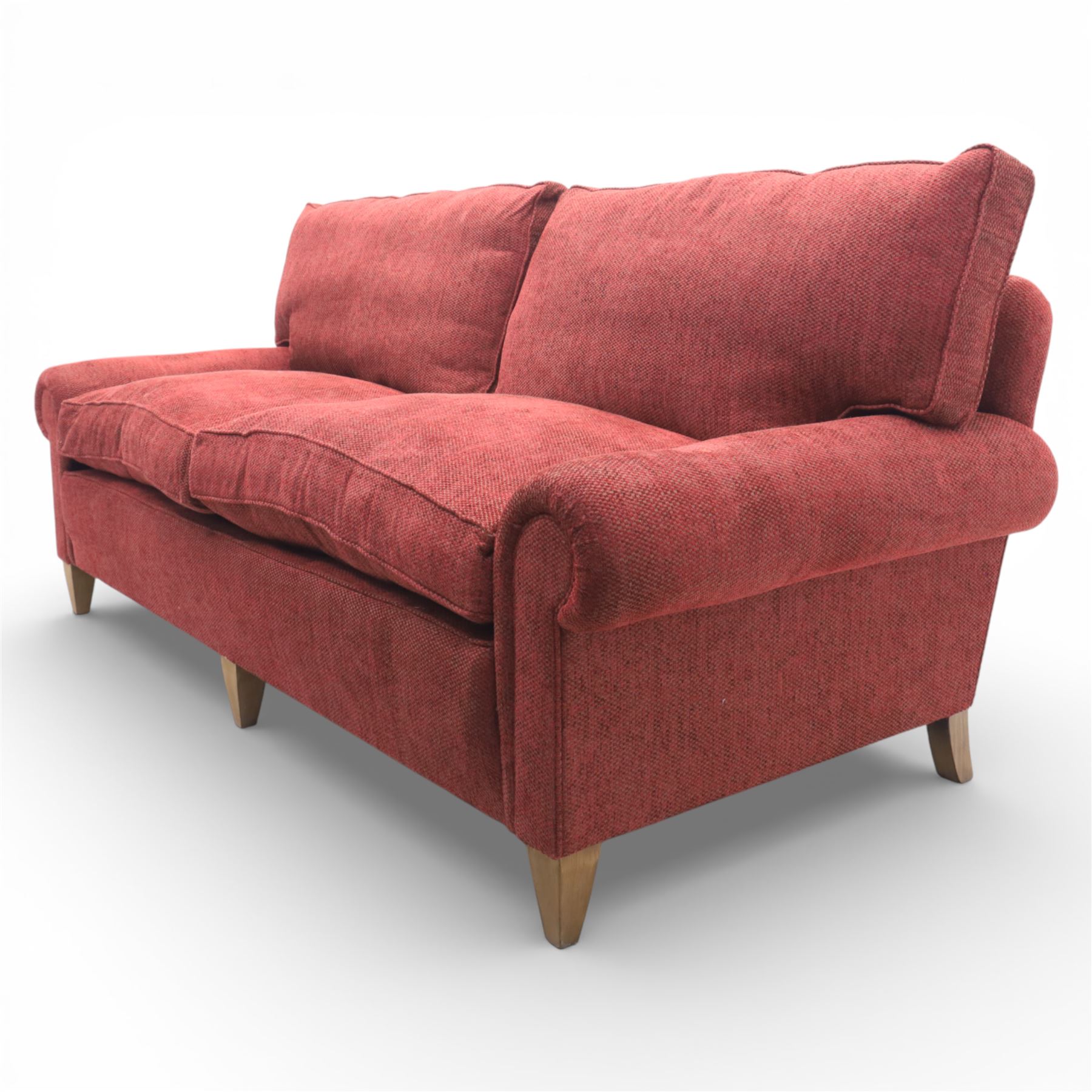 Late 20th century three seat sofa upholstered in red fabric, with gently rounded scroll arms, loose seat and back cushions, raised on tapered wooden legs