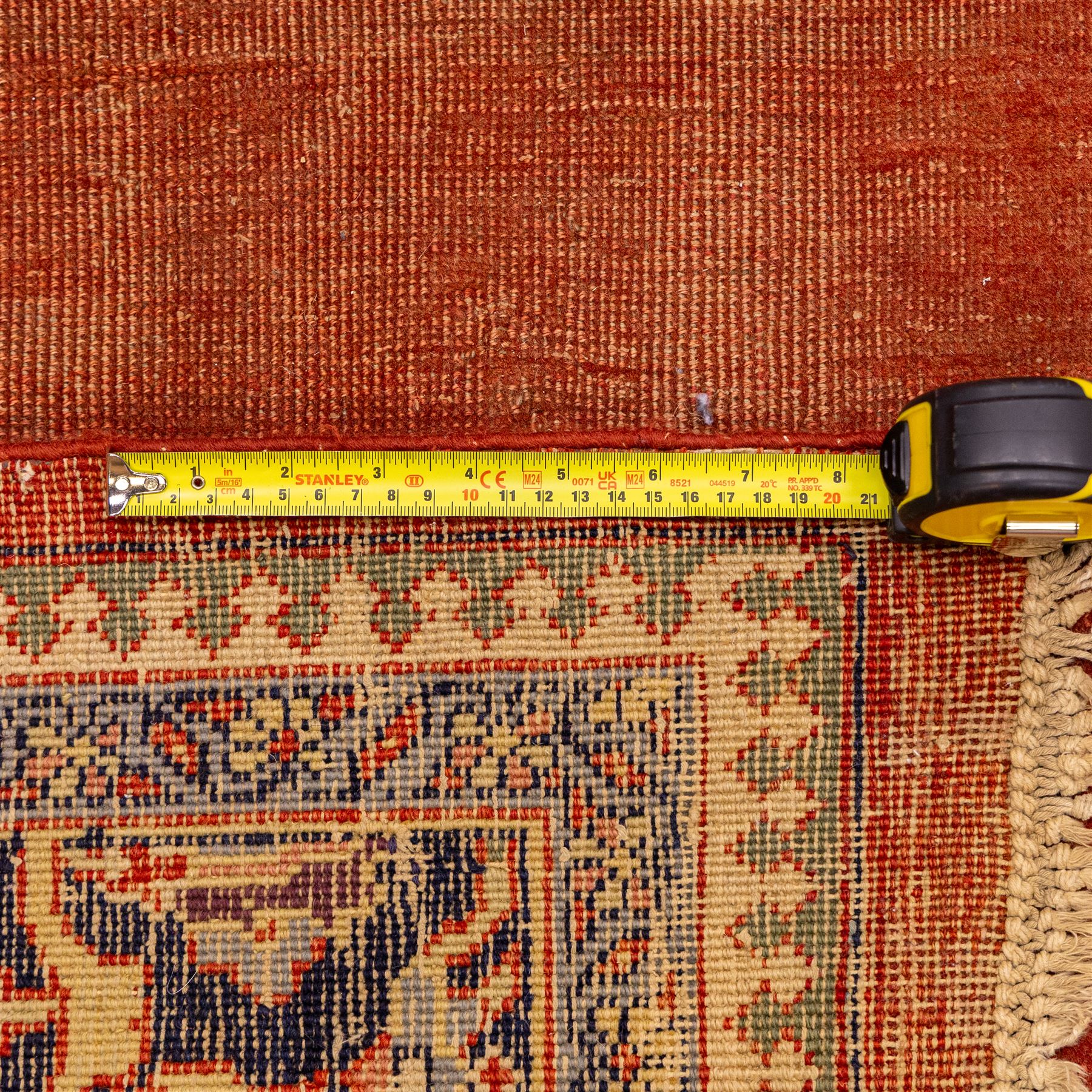 North West Persian Tabriz hand-knotted carpet, salmon field with central elongated lozenge medallion intricately filled with scrolling arabesques and palmettes, framed by stylized corner spandrels within a broad indigo main border  of bold palmettes and floral vinery between multiple guard stripes, rendered in tones of terracotta, sage green, and soft ivory, with cotton fringe ends 