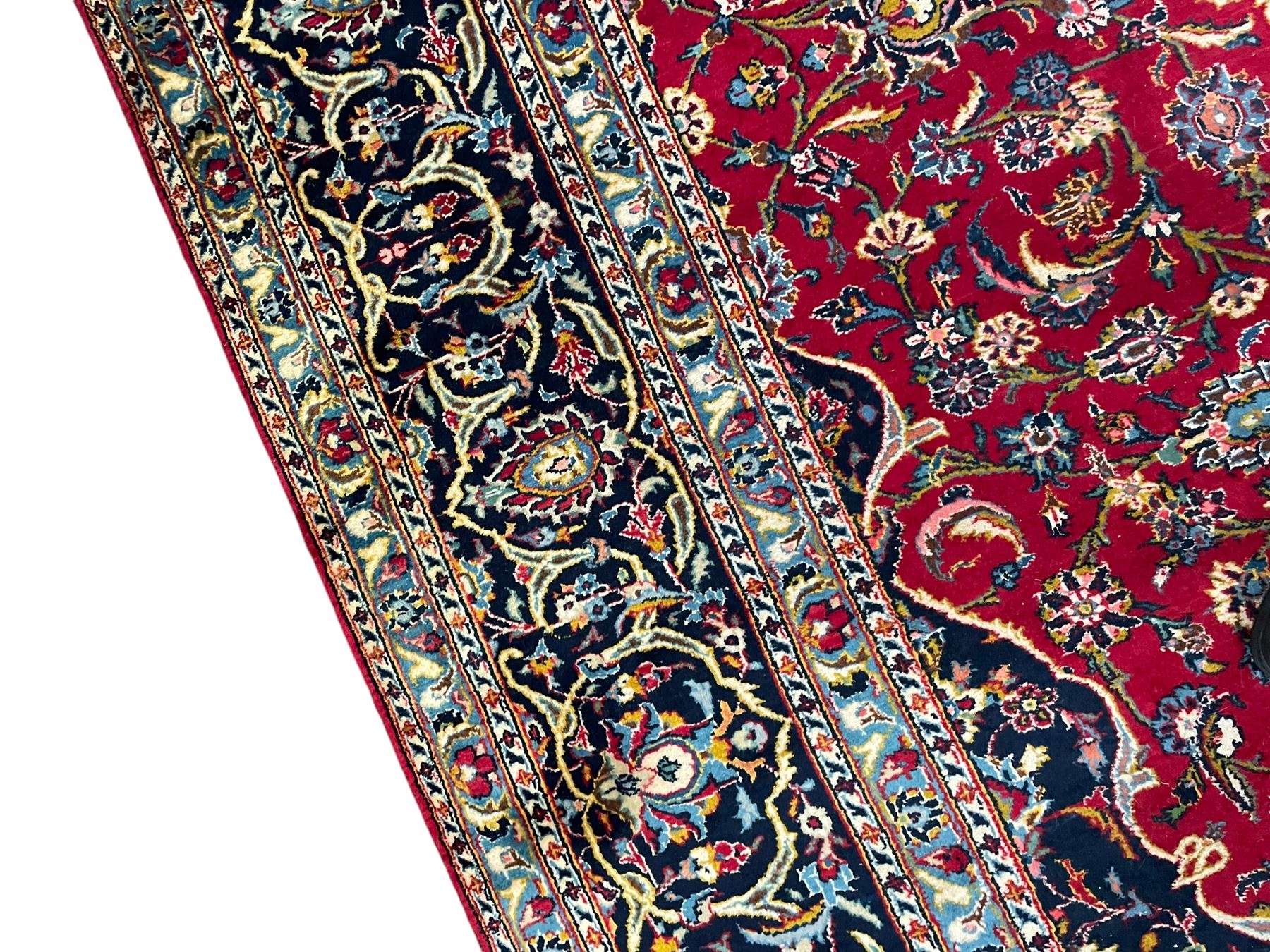 Persian Kashan crimson ground carpet, the central pole medallion decorated with flower heads, surrounded by trailing leafy branches and palmettes, scrolling border decorated with further palmettes, within floral pattern guard stripes 