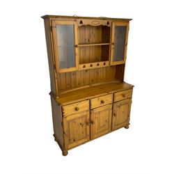 Traditional pine kitchen dresser, two-tier plate rack flanked by two glazed cupboards, base fitted with three drawers over three cupboard doors, on bun feet