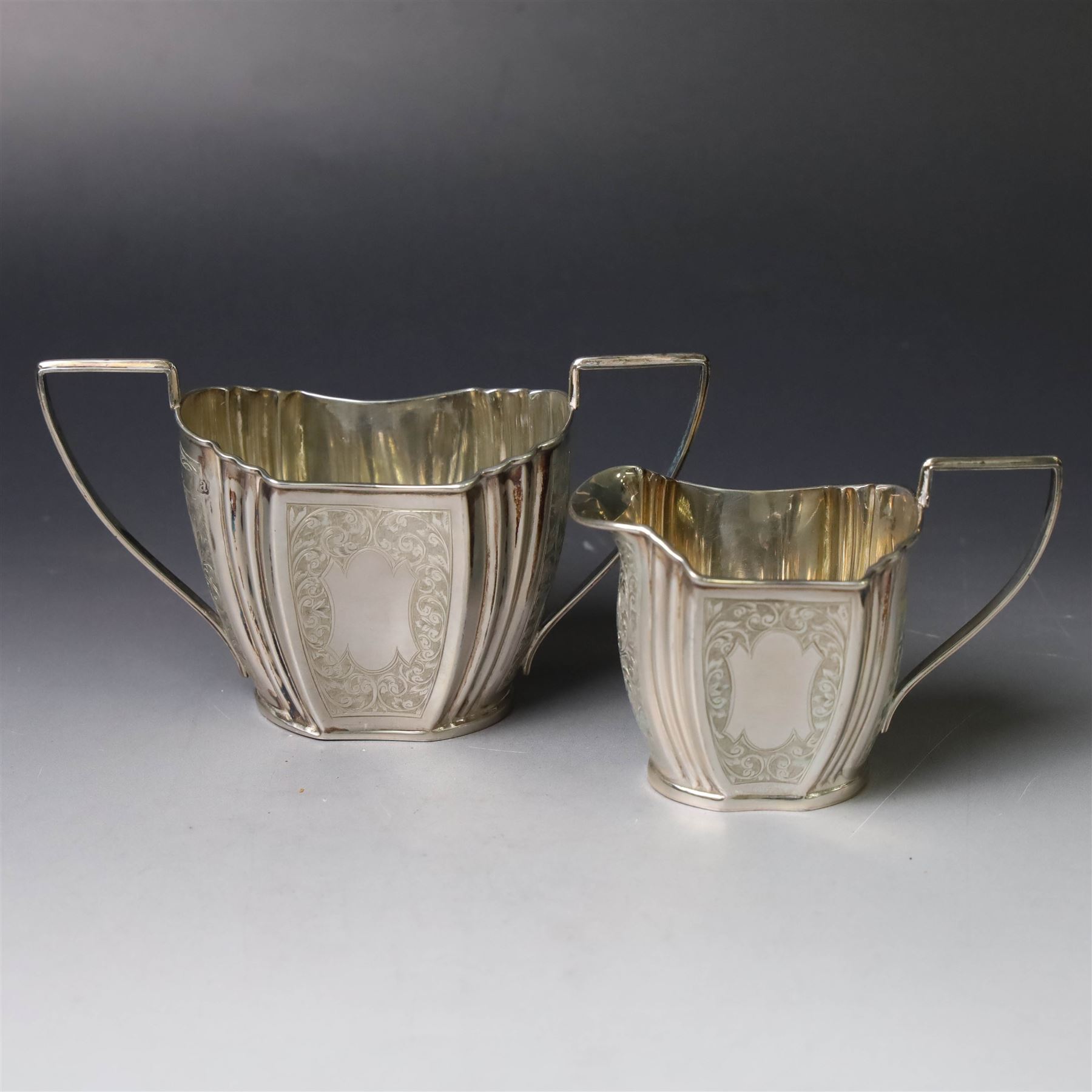 Late Victorian silver twin handled open sucrier and milk jug, of fluted form with panels of engraved foliate decoration, hallmarked D & M Davis, London 1896