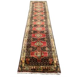 Kurdish pink ground runner, set with a series of ten floral medallions on linked field, the border decorated with stylised flower heads and bird motifs 