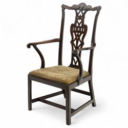 19th-century Chippendale Revival design mahogany oversized high-back armchair, serpentine crest carved top rail above pierced back splat with interlaced ribbon carving and geometric fretwork design, and outward scrolling arms above drop-in needlework seat on square chamfered legs 
