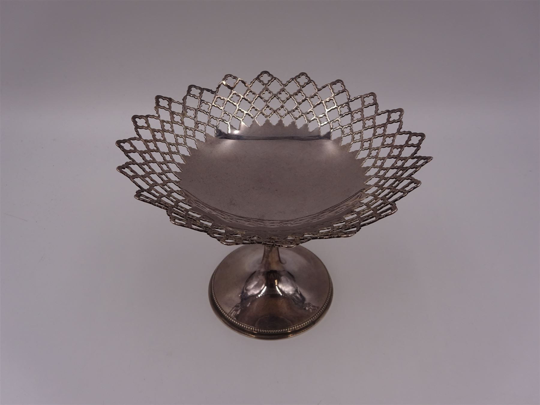 Early 20th century silver pedestal bon bon dish, of circular form, with pierced quatrefoil lattice work design sides and shaped rim, upon circular spreading beaded foot and knopped stem, H10.6cm, hallmarked Walker & Hall, Sheffield 1912