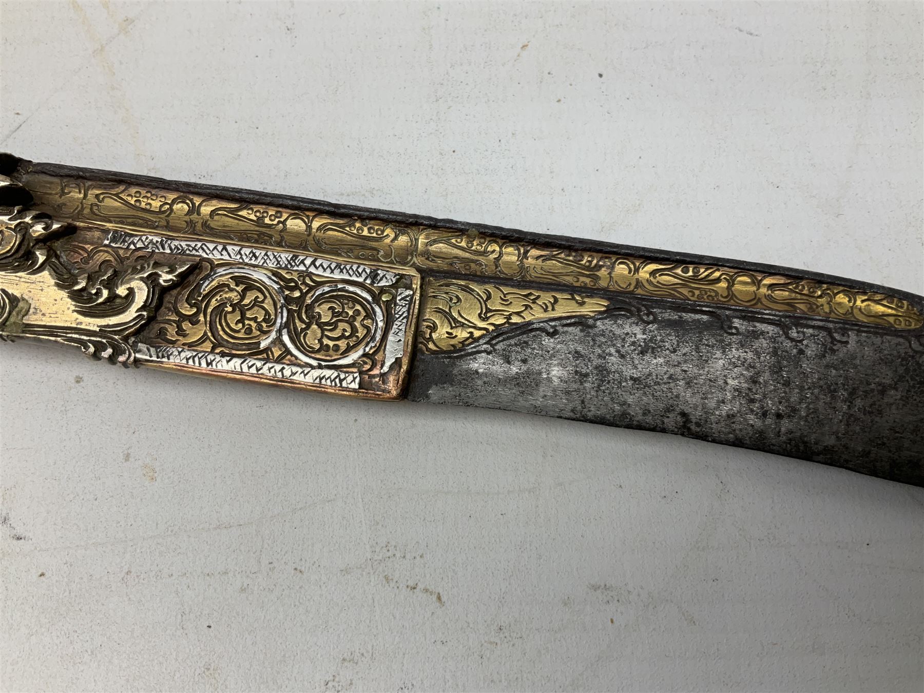 19th century Singhalese knife pia kaetta, the 20cm steel blade inset with yellow and white metal, with metal mounted carved pistol grip, in plain wooden scabbard L33cm overall