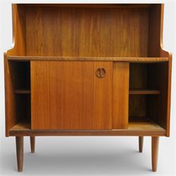 Mid 20th century Scandinavian teak bookcase cabinet in the manner of Johannes Sorth, the upper section with three open shelves over a shaped fall to a lower cupboard enclosed by sliding doors with recessed circular handles, raised on tapering supports