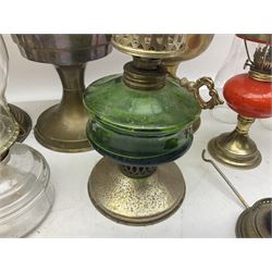 Oil lamp with a green glass reservoir, together with glass based oil lamp with glass chimney,  two brass lobed baluster form oil lamps and six similar examples