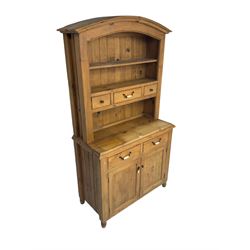 Pine farmhouse style dresser, arched top with projecting cornice over two tier plate rack and three small drawers, base fitted with two drawers with ceramic handles and two panelled cupboards, on turned feet