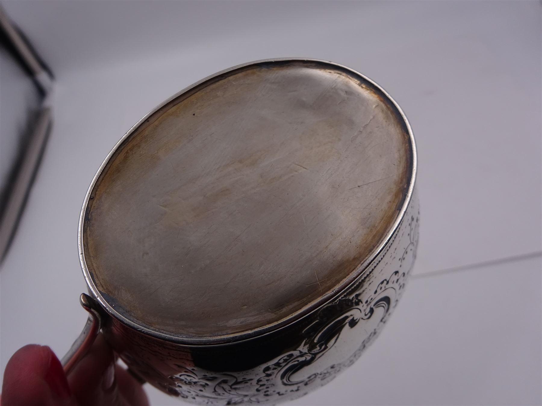 George III silver cream jug, of helmet form with angular handle, embossed with floral and scrolling decoration and engraved initial, hallmarked Edward Mayfield, London 1806, H9.3cm, together with a modern silver 'Sherry' decanter label, hallmarked Birmingham Mint, Birmingham 1986