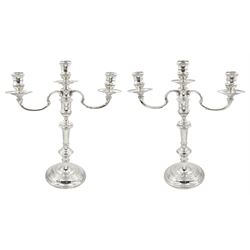 Pair of mid 20th century silver twin branch candelabra, each with filled circular stepped base leading to knopped stem and central socket with plain drip pan, supporting two curved branches with conforming sockets and drip pans, hallmarked William Comyns & Sons Ltd, London 1956, H35.5cm