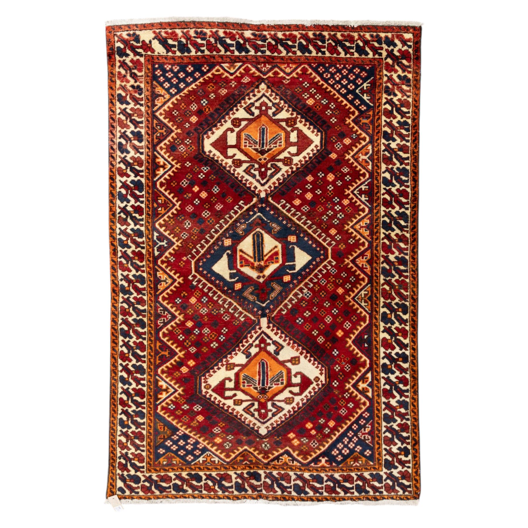 South West Persian Cori hand-knotted rug, red field with three central stepped lozenge medallions enclosing stylized geometric motifs surrounded by scattered rosette devices and angular ornaments within multiple geometric borders, with fringe ends  